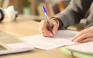 Student hands filling out form document at home