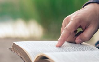 Close-up of man's hands while reading the Bible outside.Sunday readings, Bible education. spirituality and religion concept.