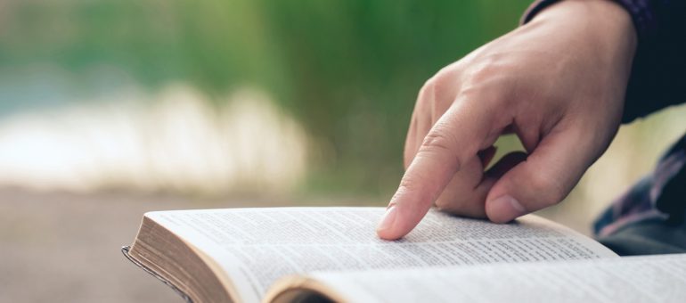 Close-up of man's hands while reading the Bible outside.Sunday readings, Bible education. spirituality and religion concept.